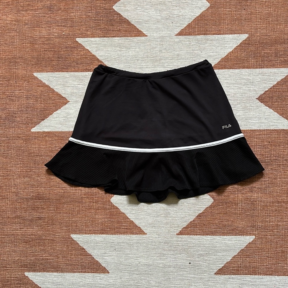 Small black Fila tennis skirt with a wavy hem.
